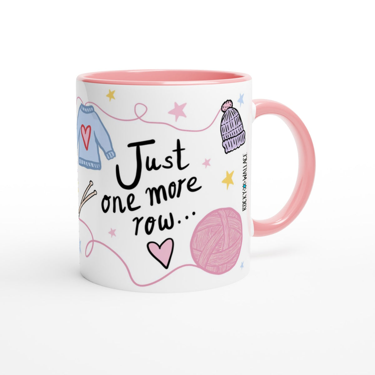 A white ceramic mug with a pink interior and handle, decorated with knitting-themed illustrations including a blue sweater, pink yarn ball, knit hat, stars, and the phrase 'Just one more row.